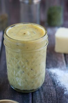 a jar filled with food sitting on top of a wooden table next to a spoon