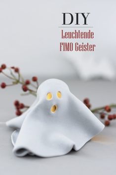 a white ghost figurine sitting on top of a table next to some red berries