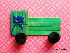 popsicle craft made to look like a green tractor with blue bow on it's head