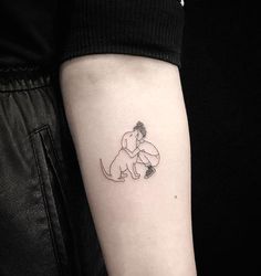 a small tattoo on the arm of a person with a dog sitting on it's back