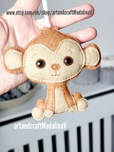 a hand holding a small stuffed monkey in it's right hand with the tag hanging from it