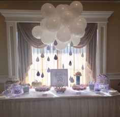 a table topped with lots of balloons and desserts next to a window covered in curtains