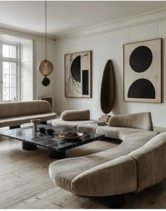 a living room filled with furniture and paintings on the wall above it's coffee table