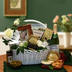 a white basket filled with wine, cheese and crackers on top of a table