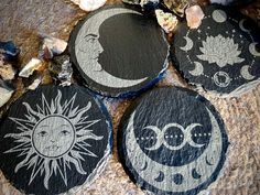 four black and white painted stepping stones with the moon and sun on them, sitting next to some rocks