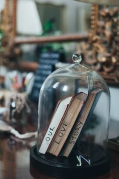 two books under a glass clochel on top of a wooden table