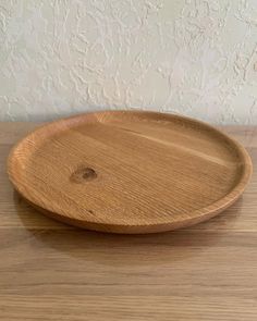 a wooden plate sitting on top of a wooden table next to a white painted wall