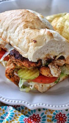 a chicken sandwich with lettuce and tomato on a plate next to potato chips