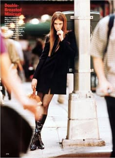 a woman standing next to a pole talking on a cell phone