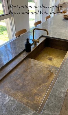 a kitchen sink sitting under a window next to a counter top with a faucet