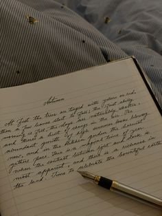 an open notebook with writing on it and a pen resting on top of it next to a pillow