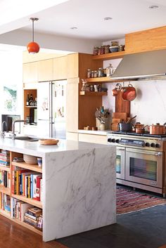 a kitchen with marble counter tops and stainless steel appliances, along with wooden shelves filled with cookware