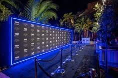 a large display on the side of a building in front of palm trees at night