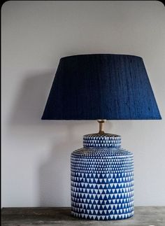 a blue lamp sitting on top of a table next to a black and white vase