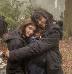 two women hugging each other in the woods on a foggy day with trees behind them