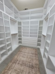 an empty walk - in closet with white shelving and beige rug on the floor