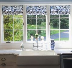 a kitchen sink under a window with blue and white decor on the windowsills