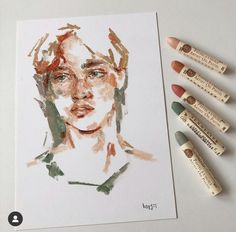 some crayons are next to a drawing of a woman's face