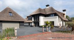 a large white house with two thatched roofs on it's roof and driveway