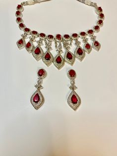 Enhance your special occasion look with our CZ American Diamond Necklace. Perfect for weddings, parties, or as a gift. Its red stones add a touch of elegance to any outfit, such as a saree, gown, or lehanga. Elevate your style with this stunning accessory. This jewellery set includes a necklace and matching earrings. Jewellery Care- Keep the jewellery dry, avoid contact with perfumes and water. American Diamond Necklaces, Saree Gown, Bridal Choker, Red Stones, A Necklace, Jewellery Set, American Diamond, Red Stone, Bridal Sets