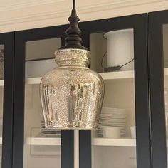 a glass jar is hanging from the ceiling in front of shelves with plates and cups