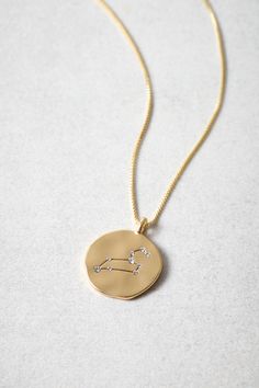 a gold necklace with a zodiac sign on it