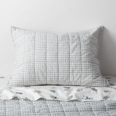 a bed with a white and blue checkered comforter on it, next to a pillow