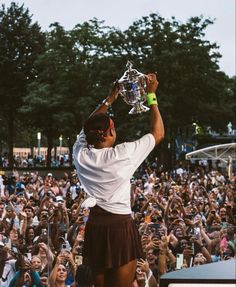 a man holding up a trophy above his head in front of a large group of people