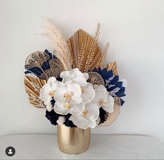 a gold vase filled with white and blue flowers