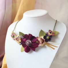 a white mannequin with a purple flower and green leaves on it's neck