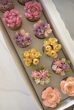 cupcakes decorated with pink and yellow flowers in a box