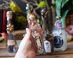 a person holding an empty bottle in front of some miniature bottles on a wooden table