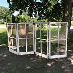 an open window sitting next to a tree in the middle of a park on a sunny day