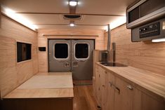 the inside of an rv with wood paneling and stainless steel appliances on each side