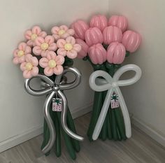 two vases with flowers in them sitting next to each other on the floor near a wall