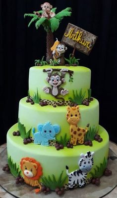 a three tiered cake decorated with animals and palm trees