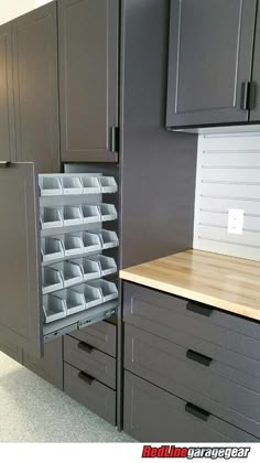 a kitchen with gray cabinets and drawers in the middle is open to reveal an empty drawer