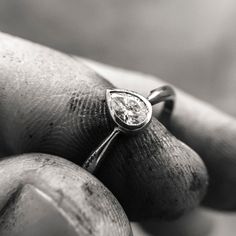 a close up of a person's hand holding a ring with a diamond on it