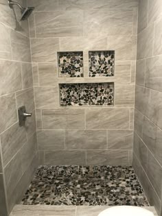 a white toilet sitting in a bathroom next to a walk in shower and tiled walls