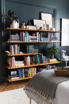 a bed sitting in front of a book shelf filled with books