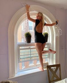 a woman standing on a window sill with her legs in the air