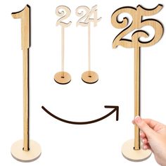 a hand holding a wooden clock with the numbers twenty five and twenty four on it