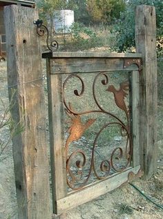 an old wooden gate with a bird design on the top and bottom, in front of a fence