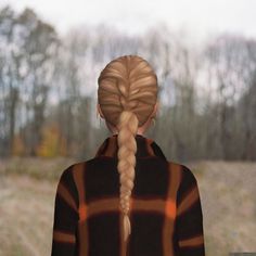 a woman with long blonde hair standing in front of a field