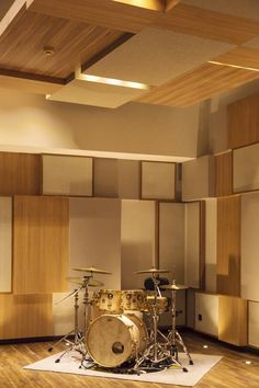 a drum set sitting on top of a hard wood floor next to a wooden paneled wall