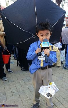 a young boy holding an umbrella and wearing a blue shirt