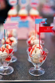 some ice cream sundaes with strawberries and flags in them on a table