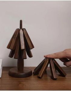 a wooden sculpture is on a table with a person's hand reaching for it