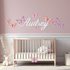 a baby's room with pink and purple butterflies on the wall, and a crib in the foreground