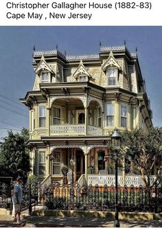 an old victorian house is painted yellow and has white trim on the front porch, with wrought iron fence surrounding it